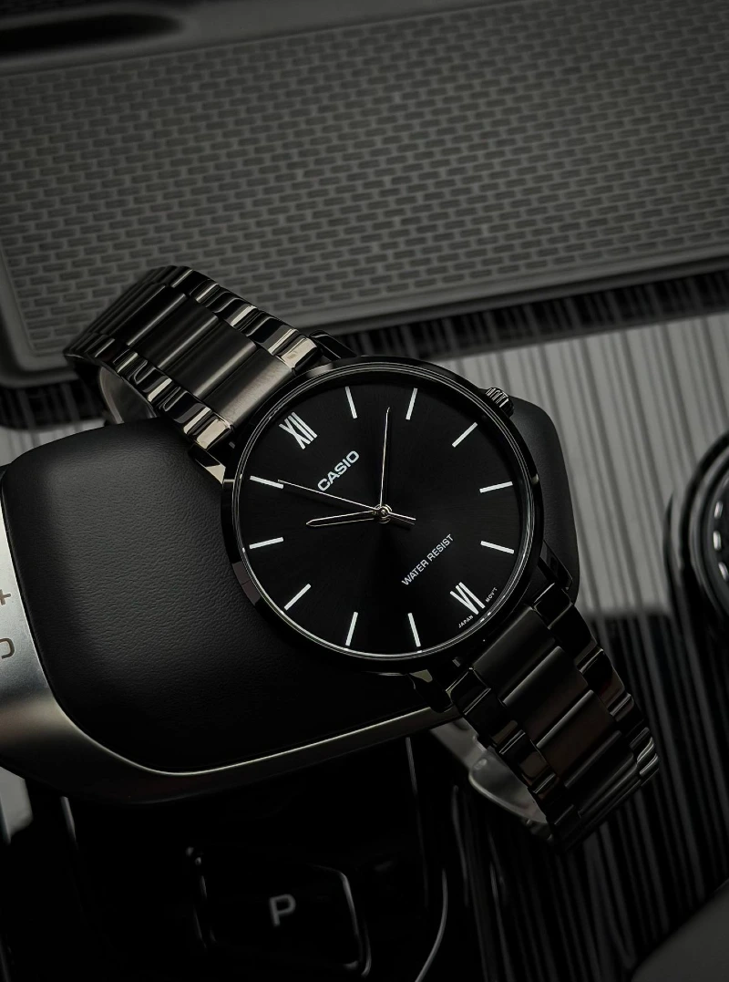 All-Black Quartz Watch with Roman Numerals on Car Console
